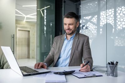 smiling-businessman-working-on-laptop-in-modern-of-2024-06-12-17-02-24-utc.jpeg